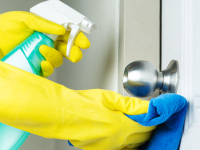 Spraying a door handle with a disinfectant spray