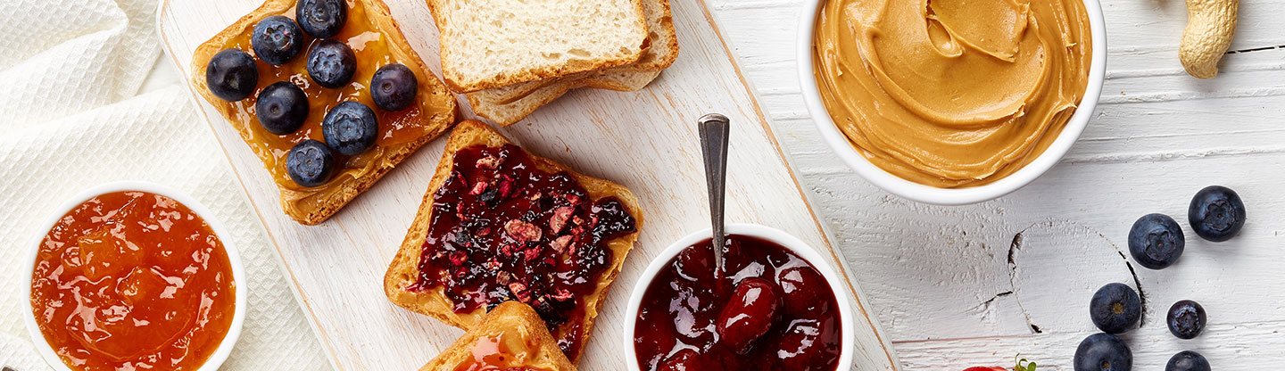 An overhead photo of a breakfast spread with jam and peanut butter